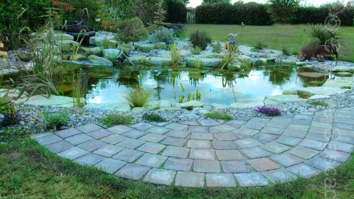 Fish pond with small waterfall, Halsted, surrounding planting and paving by client. The pond uses the ecosystem method to keep water healthy. An intake skimmer bay draws leaves and other matter to one convenient location, without which detritus would gradually collect on the pond bottom. A pond like this should require an annual clean-out which is a simple procedure done by us or the client.  - Landscaping and Water Features -  Creative Cascades